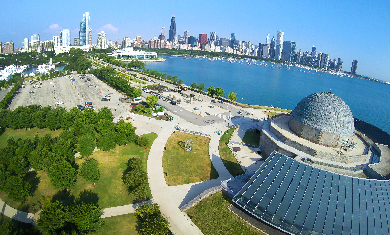 An aerial view of the Adler Planetarium with Chicago's skyline featured in the background.